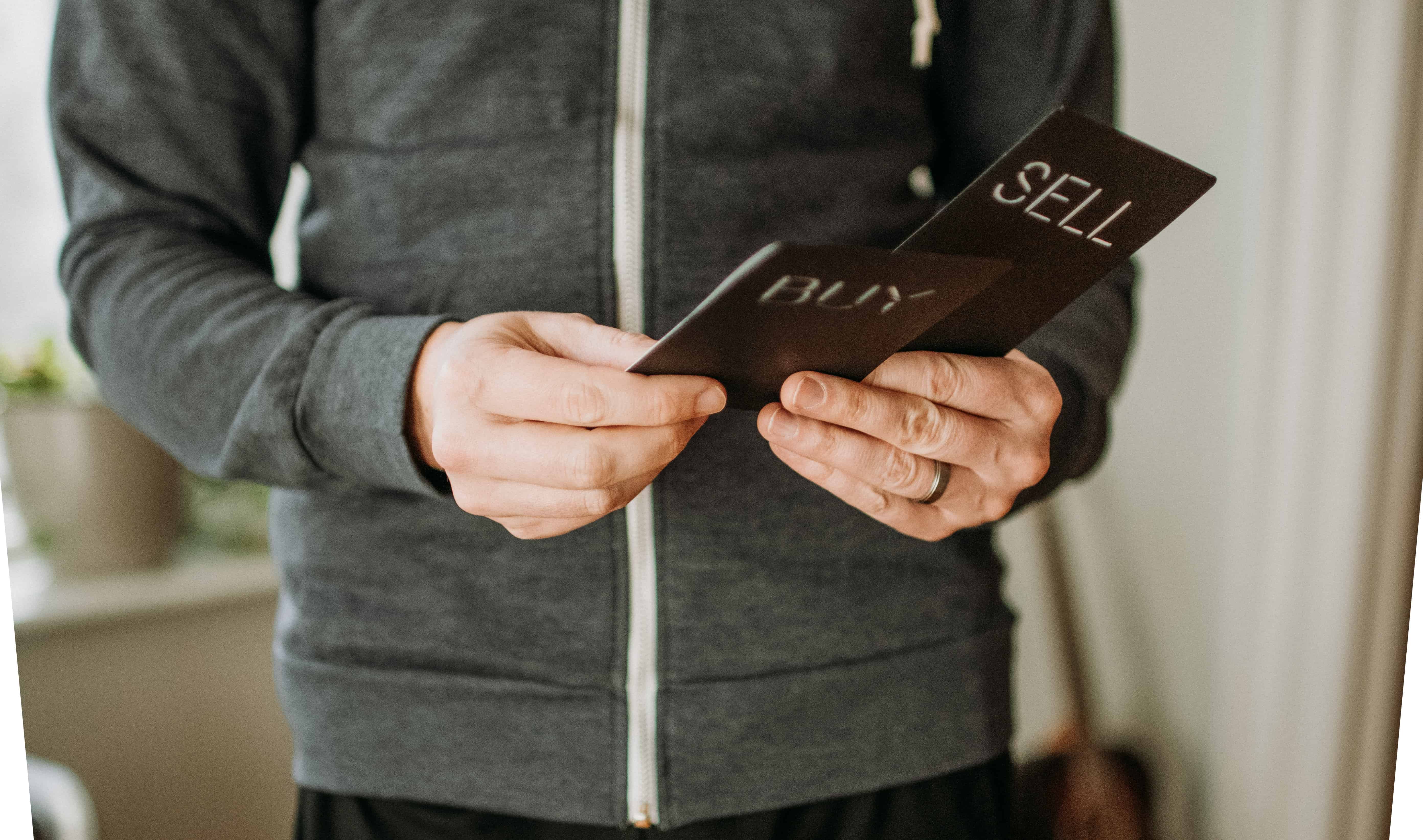 A man holding 2 cards (Buy and Sell)